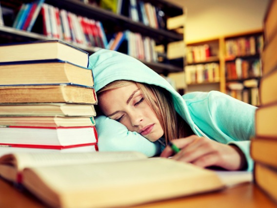 a girl falling asleep around books
