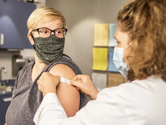 Doctor putting bandaid on person's arm in doctors office