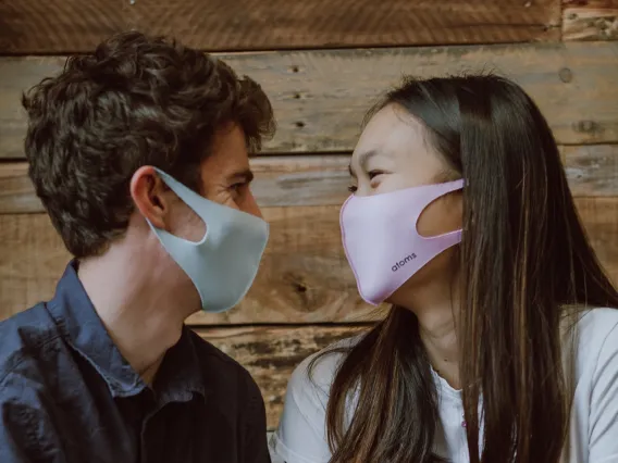 Male and female holding hands looking at eachother wearing masks