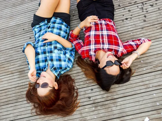 Two people laying down with sunglasses laughing