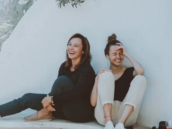 Two girls sitting down laughing