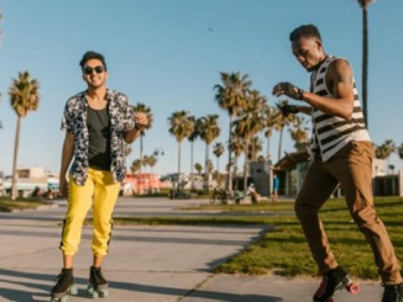 Two people roller blading on sidewalk with palm trees and blue sky