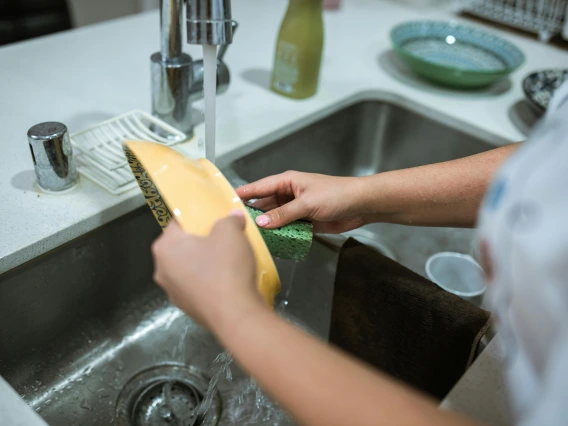 close-up of a person's hands washing dishes at a sink