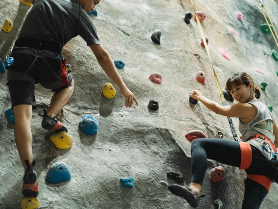 2 people climbing on rock wall with harnesses