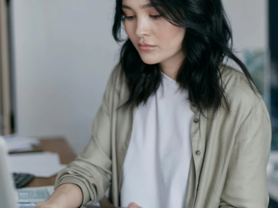 person holding a card and typing on a laptop computer