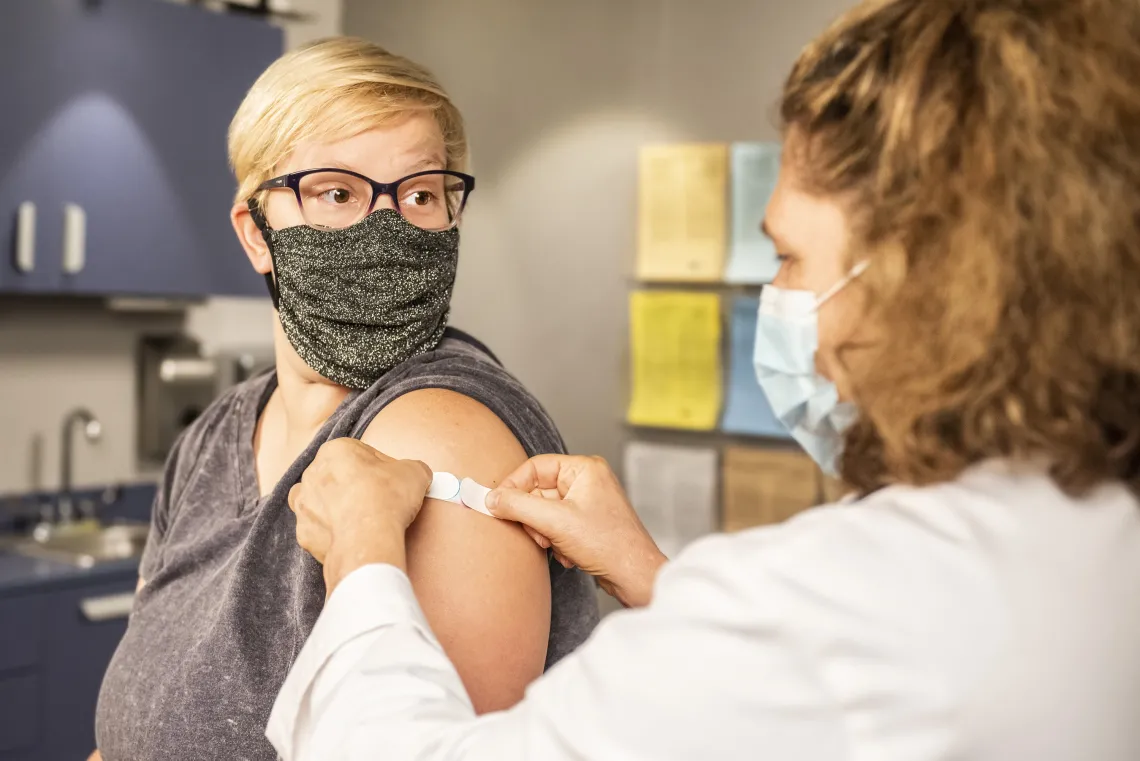 Doctor putting bandaid on person's arm in doctors office