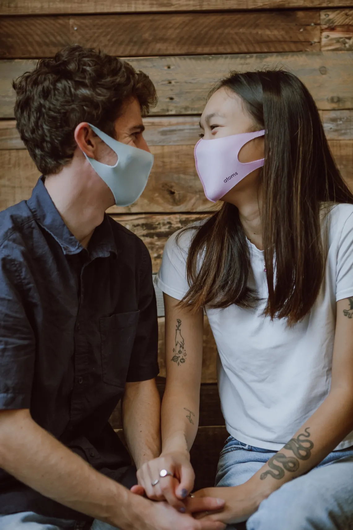 Male and female holding hands looking at eachother wearing masks