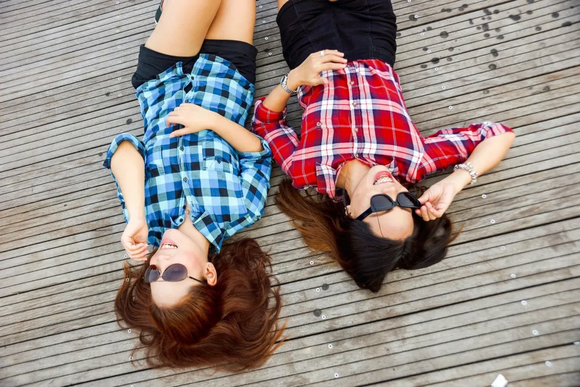 Two people laying down with sunglasses laughing