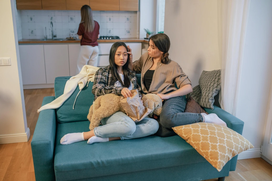 People sitting on couch comforting each other