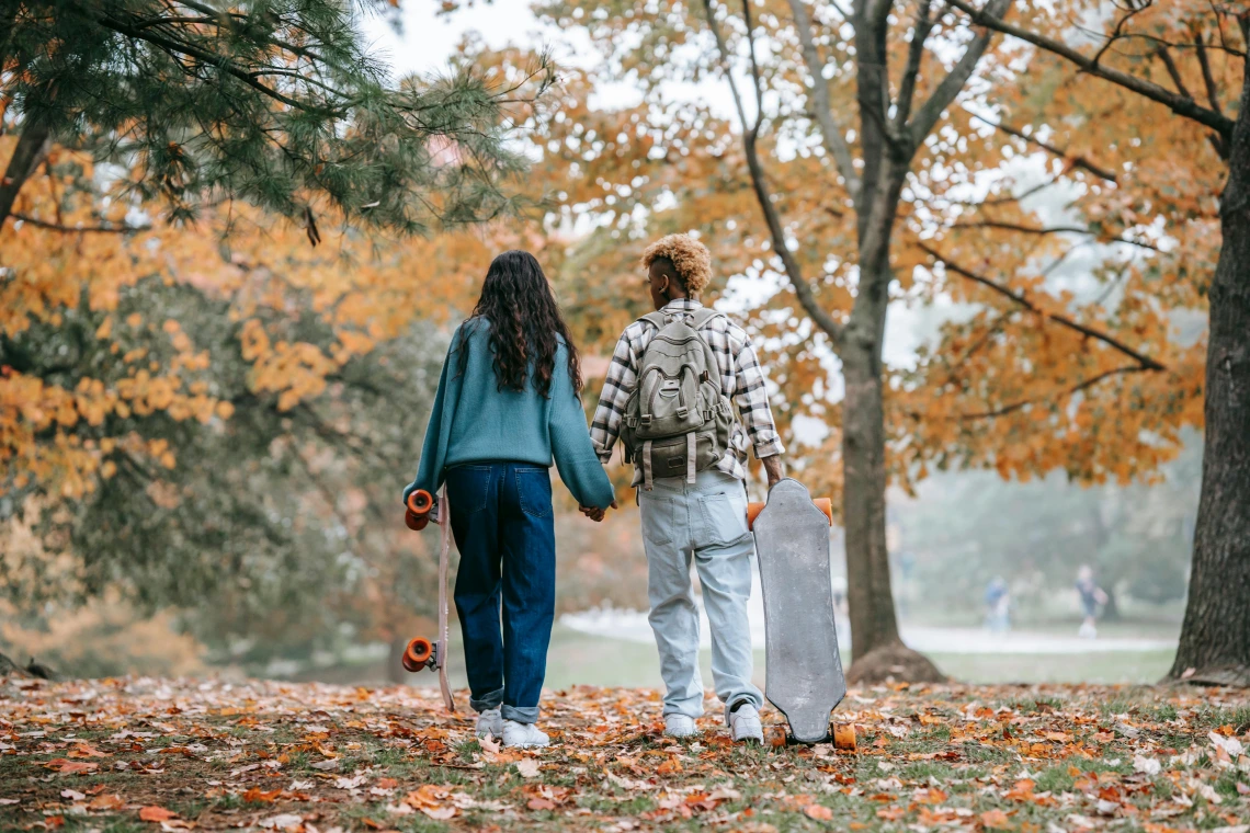 Two people walk during fall in a park